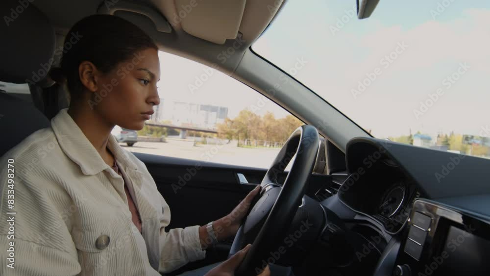 Medium shot of concentrated female African American student sitting in learners car adjusting steering wheel before starting driving session Medium shot of concentrated female African American student sitting in learners car adjusting steering wheel before starting driving session