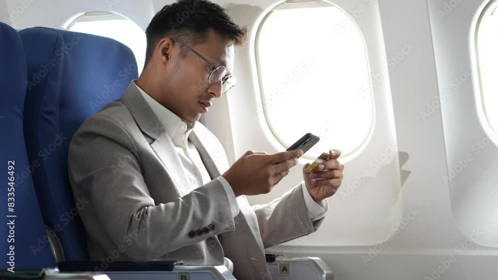 Stress businessman sitting in airplane and holding credit card in hand, while sitting in the airplane, Passengers near the window. Stress businessman sitting in airplane and holding credit card in hand, while sitting in the airplane, Passengers near the window.
