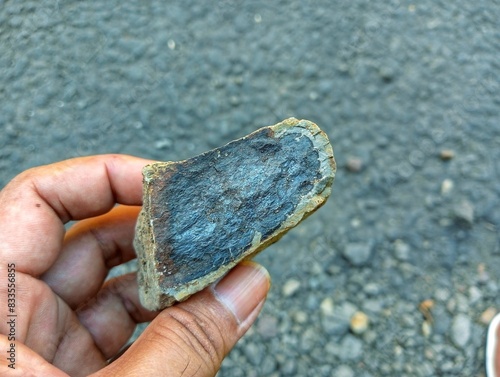 a hand holding rock containing Iron ore natural minerals in the mine. Stone texture of open pit. Extraction of minerals for heavy industry - the texture of the rock containing iron ore and copper.