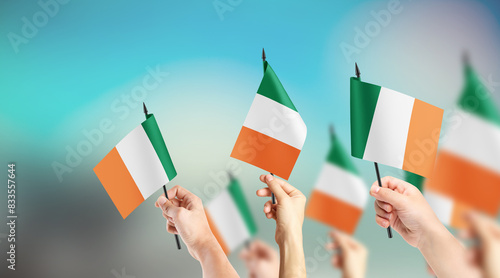 A group of people are holding small flags of Ireland in their hands. photo