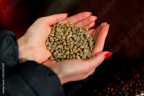 Close-up of girl holding freshly green coffee in her hands at a roasting factory