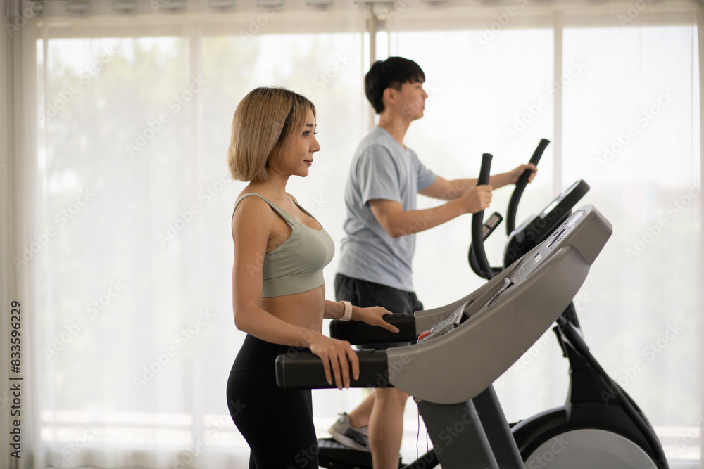 Young man and woman running on treadmills with curtain Young man and woman running on treadmills with curtain