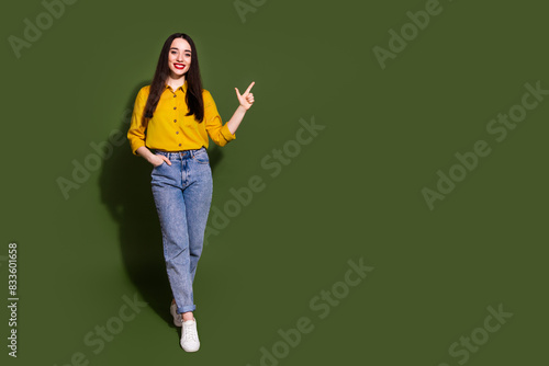 Full length photo of adorable lovely girl wear yellow shirt showing empty space isolated green color background © deagreez