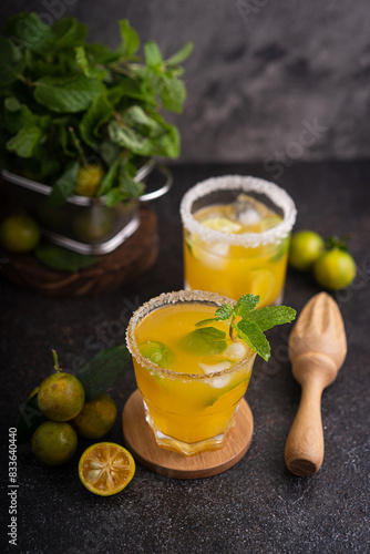 Fresh summer orange mojito with tangerine orange, mint and ice on black background