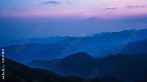 The image shows a beautiful mountain landscape with a blue sky and purple clouds. The mountains are in the distance and are covered in mist.