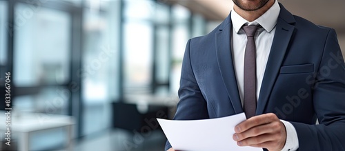 In the office a recruiter in formal attire can be seen appearing cheerful as they hold a document and pencil The image showcases ample copy space