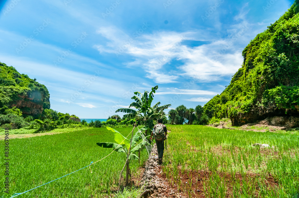 Gunungkidul, Indonesia - December 26, 2016. Asian man walks exploring towards Ngelangkap beach during the day.