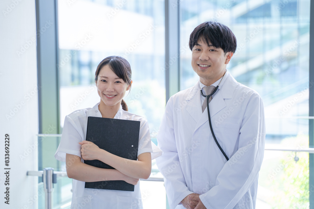 病院で笑顔で会話する男性医師と看護師 病院で笑顔で会話する男性医師と看護師