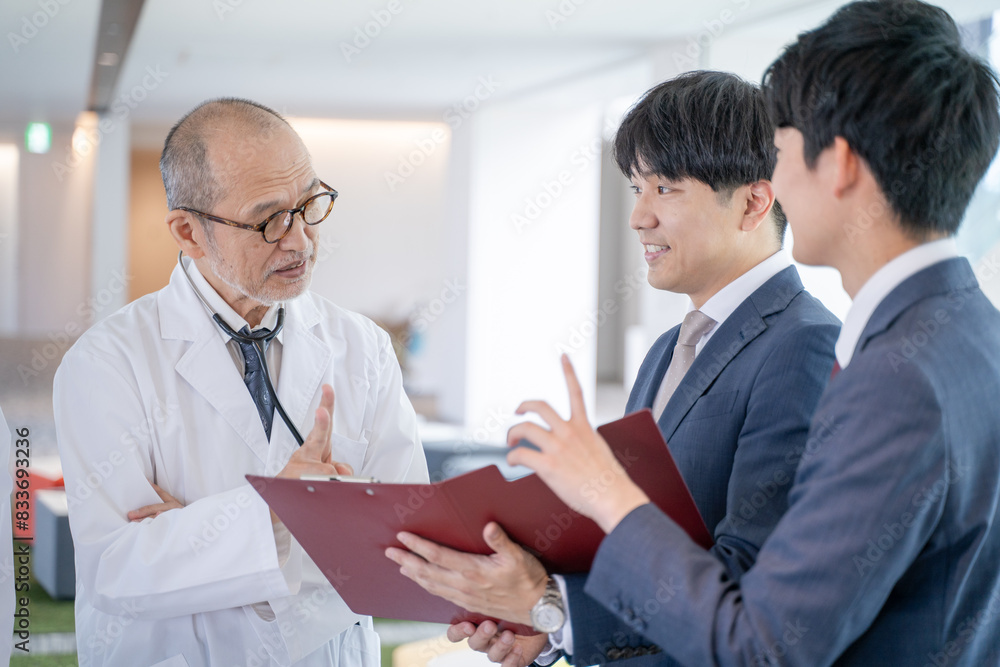 Obraz premium 病院で笑顔で会話する男性医師と医薬情報担当者MR