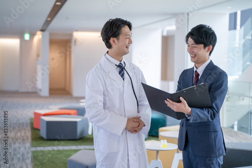 病院で笑顔で会話する男性医師と医薬情報担当者MR