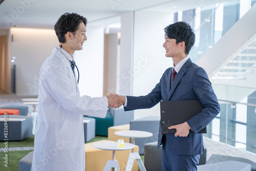 病院で握手する男性医師とビジネスマン