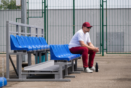 sportsman with a bottle of water sitting and resting at the seats at the stadium