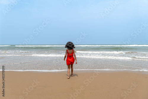 Seaside Solitude Child in Red Dress Contemplates Ocean