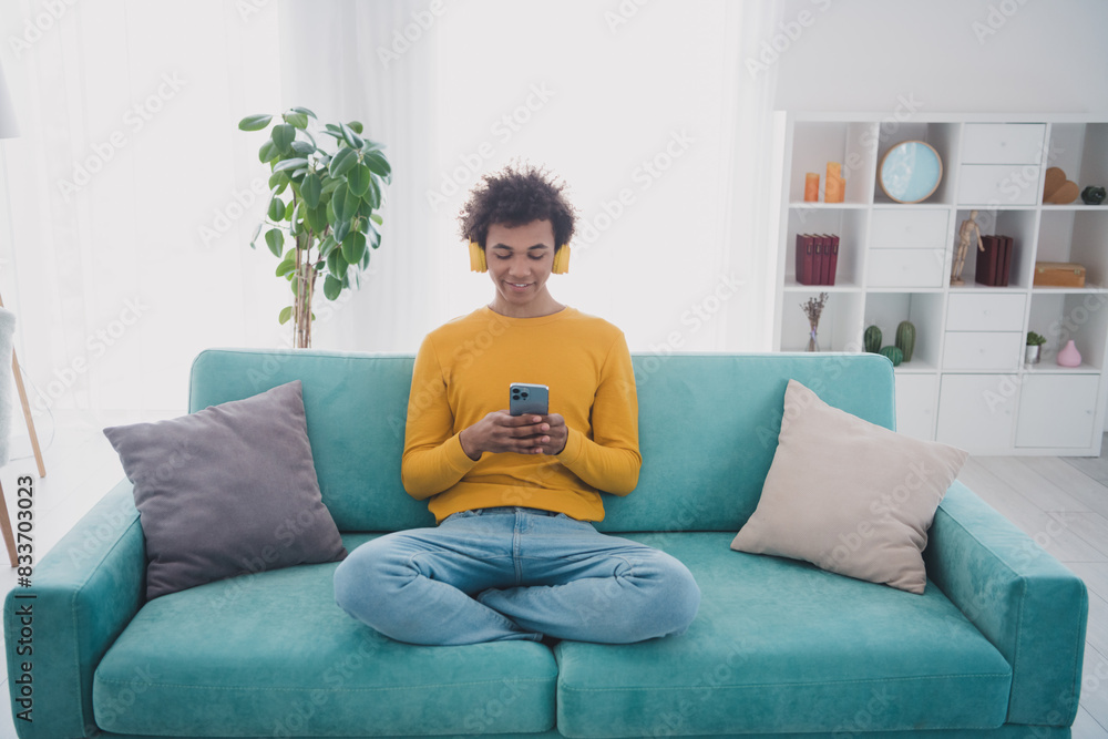 Full length portrait of nice young man use phone wear pullover white interior flat indoors Full length portrait of nice young man use phone wear pullover white interior flat indoors