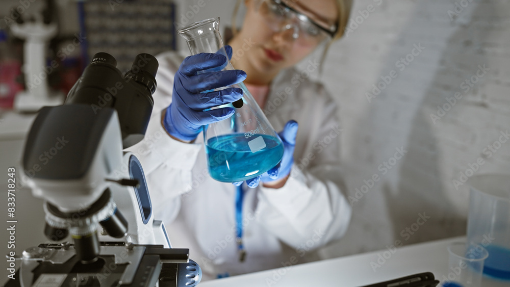 A young woman scientist examines a chemical in a flask in a laboratory setting. A young woman scientist examines a chemical in a flask in a laboratory setting.