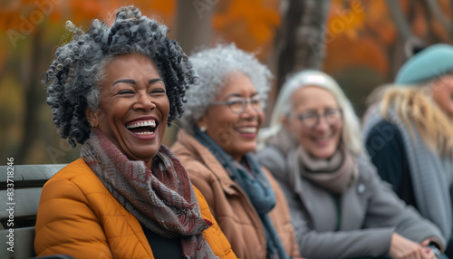 a detailed image of a woman laughing and chatting with her friends as they sit on a park bench, enjoying the pleasant weather, Multiracial Group, People, Senior people, Friendship,