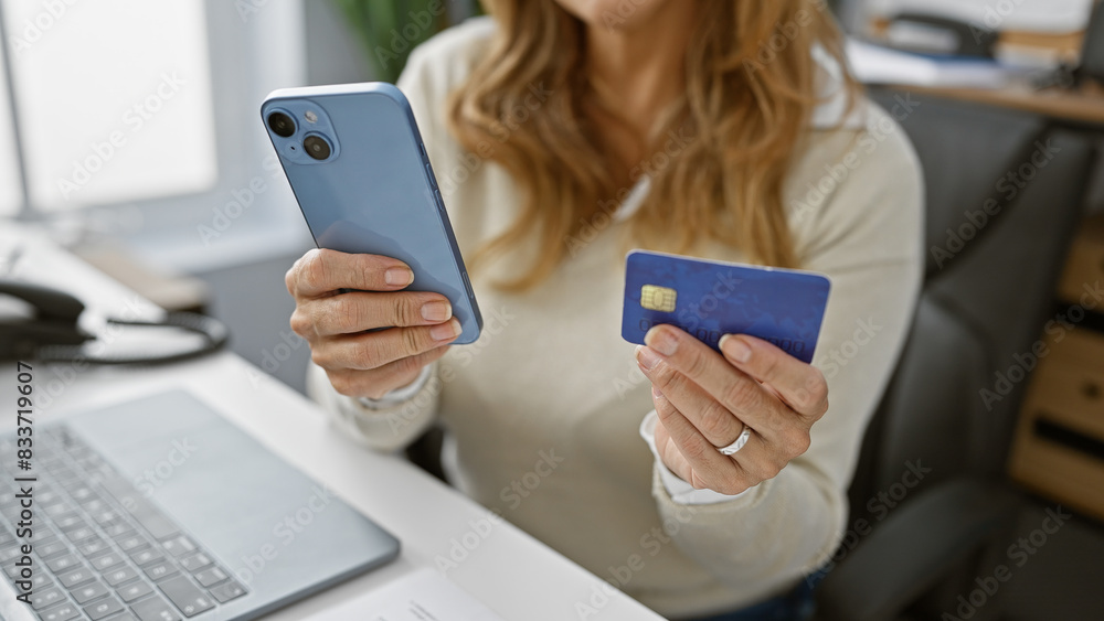 A confident woman holds a credit card and smartphone in an office, symbolizing ecommerce and financial transactions. A confident woman holds a credit card and smartphone in an office, symbolizing ecommerce and financial transactions.
