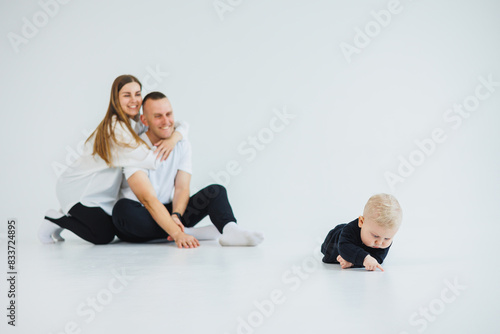 Young happy family couple with baby son on white background. Mom and dad with a baby on a white background.