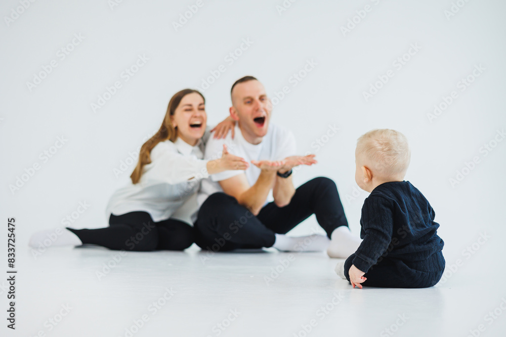 Young happy family couple with baby son on white background. Mom and dad with a baby on a white background. Young happy family couple with baby son on white background. Mom and dad with a baby on a white background.