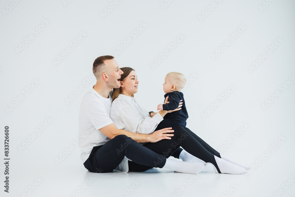 Young happy family couple with baby son on white background. Mom and dad with a baby on a white background. Young happy family couple with baby son on white background. Mom and dad with a baby on a white background.