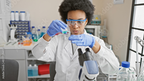 Focused african woman scientist examines test tubes in a laboratory setting  portraying professionalism and healthcare advancements.