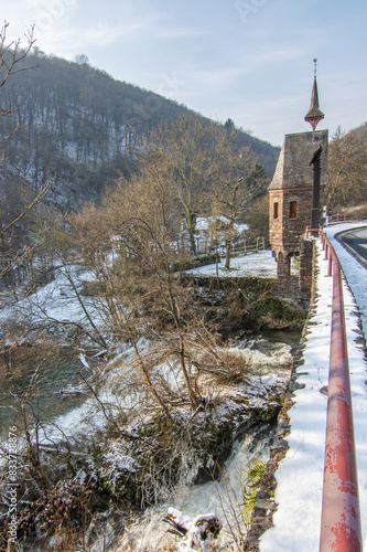 Beautiful landscape in winter with ice and snow. Waterfall of the River Elz near Pyrmont Castle, the Pyrmonter Mühle country inn is right on a lake. A historical bridge in Rhineland Pflaz, Germany photo