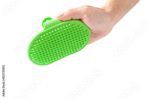 A hand holding a green pet grooming brush made of silicone on a white background.