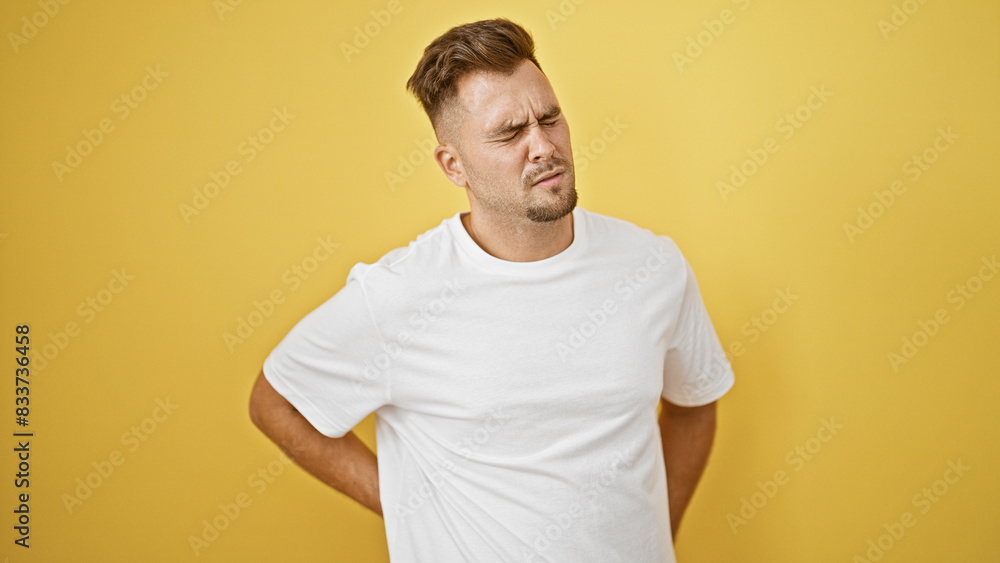 Handsome hispanic man with beard in pain isolated on yellow background Handsome hispanic man with beard in pain isolated on yellow background