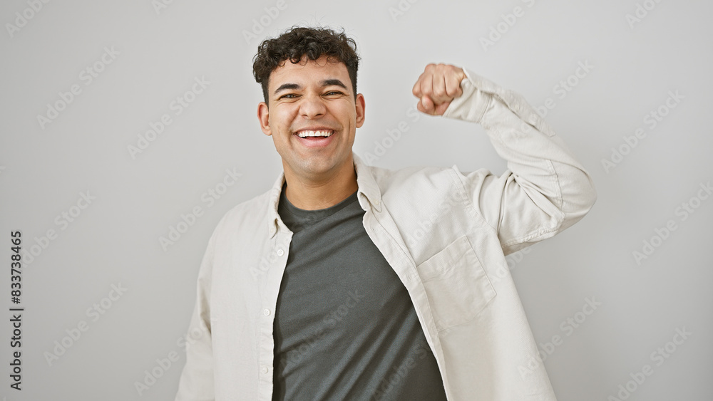 Handsome man making a strong arm gesture against a white background, smiling confidently. Handsome man making a strong arm gesture against a white background, smiling confidently.