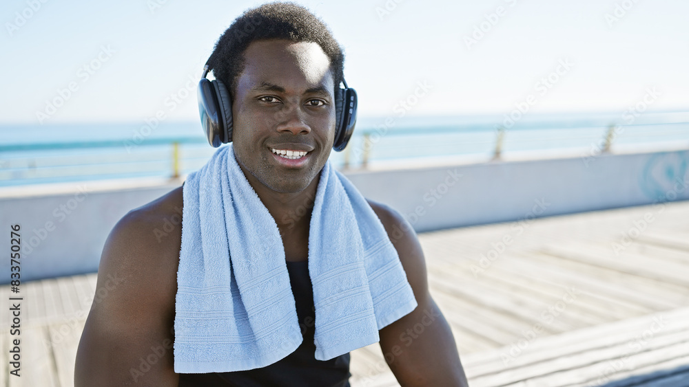 A cheerful young man with headphones enjoys a sunny day on a beachside promenade. A cheerful young man with headphones enjoys a sunny day on a beachside promenade.