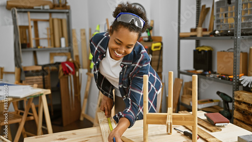 Bild auf Leinwand Smiling woman measuring wood in a carpentry workshop, embodying craftsmanship and diy spirit