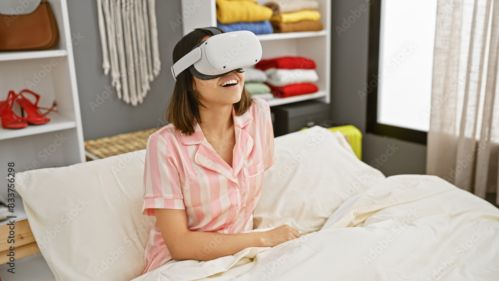 Smiling young woman wearing virtual reality headset in a modern bedroom Smiling young woman wearing virtual reality headset in a modern bedroom
