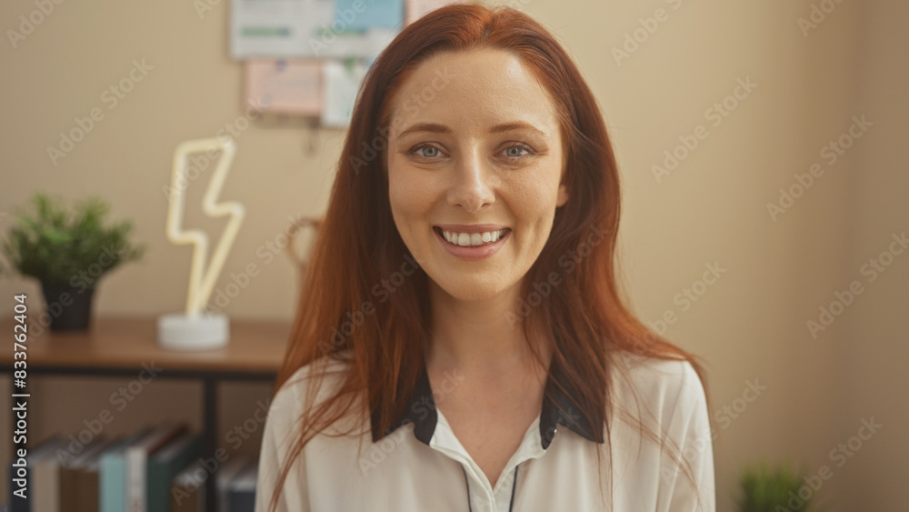 Smiling redhead woman in casual attire standing in a modern home office Smiling redhead woman in casual attire standing in a modern home office
