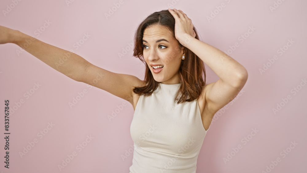 A surprised young woman with a stylish hairstyle stands against a solid pink background, expressing a playful gesture. A surprised young woman with a stylish hairstyle stands against a solid pink background, expressing a playful gesture.
