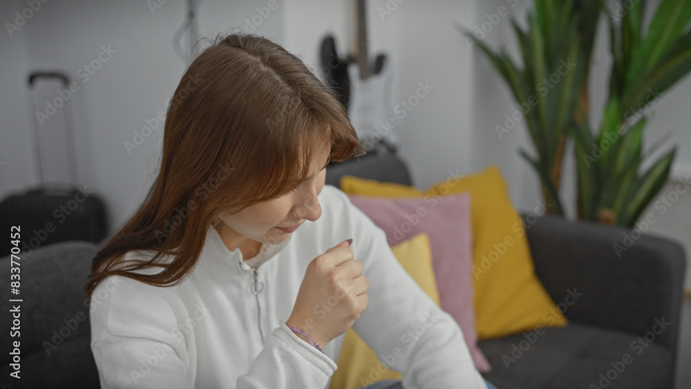 A young caucasian woman coughing in a comfortable home setting, surrounded by pillows and couch. A young caucasian woman coughing in a comfortable home setting, surrounded by pillows and couch.