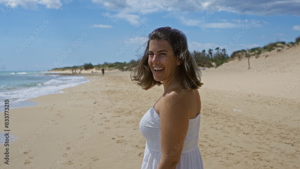 A beautiful young hispanic woman smiling at the beach in pescoluse, puglia, italy with a bright sky and sandy shoreline. A beautiful young hispanic woman smiling at the beach in pescoluse, puglia, italy with a bright sky and sandy shoreline.