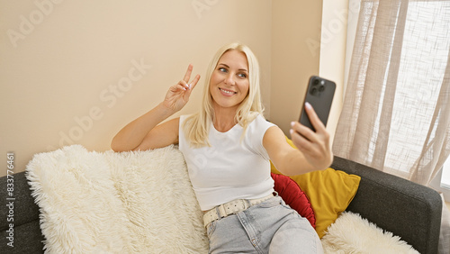 Tableau sur toile Blonde bombshell alert! radiant young woman strikes victory v with two fingers,