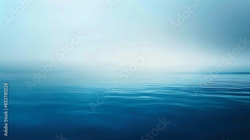 A serene seascape with a calm blue ocean and a misty horizon. The image evokes a sense of tranquility and peace.