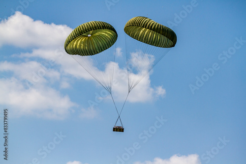 Two parachutes are flying in the sky carrying cargo