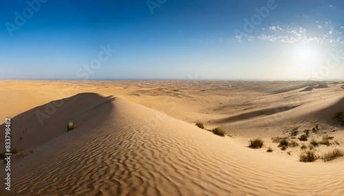 A panoramic view of a desert landscape with sand dunes and a clear blue sky. AI generated