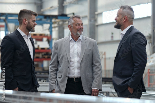 A group of three men stand side by side, possibly discussing business matters related to inheritance and the family business transfer.