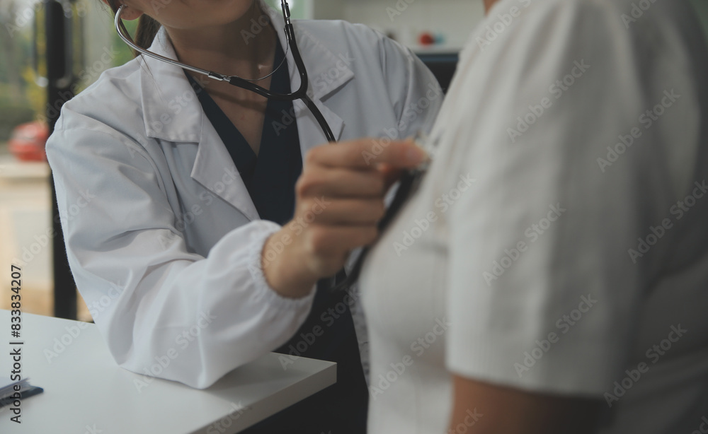 Doctor using sphygmomanometer with stethoscope checking blood pressure to a patient in the hospital. Doctor using sphygmomanometer with stethoscope checking blood pressure to a patient in the hospital.