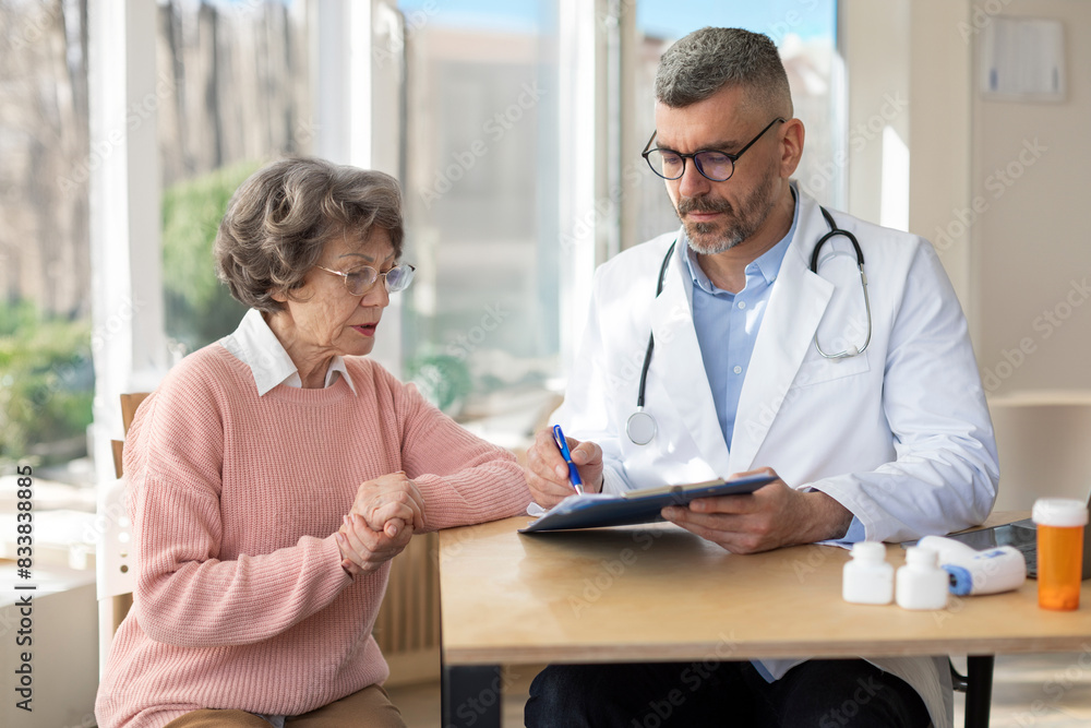 Man doctor in uniform with stethoscope holding documents, consulting older woman about checkup result, mature patient listening to physician explaining prescription Man doctor in uniform with stethoscope holding documents, consulting older woman about checkup result, mature patient listening to physician explaining prescription