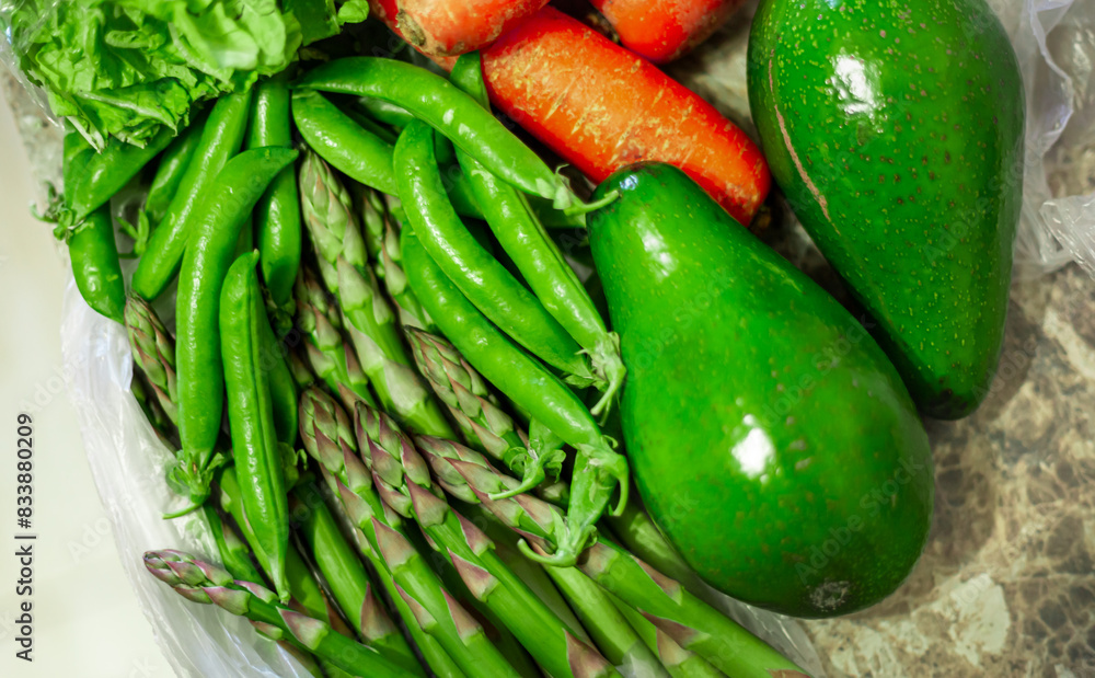 Ripe whole green avocados close up. Carrots, asparagus officinalis, green peas, green lettuce leaves. Ripe whole green avocados close up. Carrots, asparagus officinalis, green peas, green lettuce leaves.