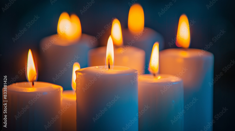 White candles with burning flames in a dark setting. White candles with burning flames in a dark setting.