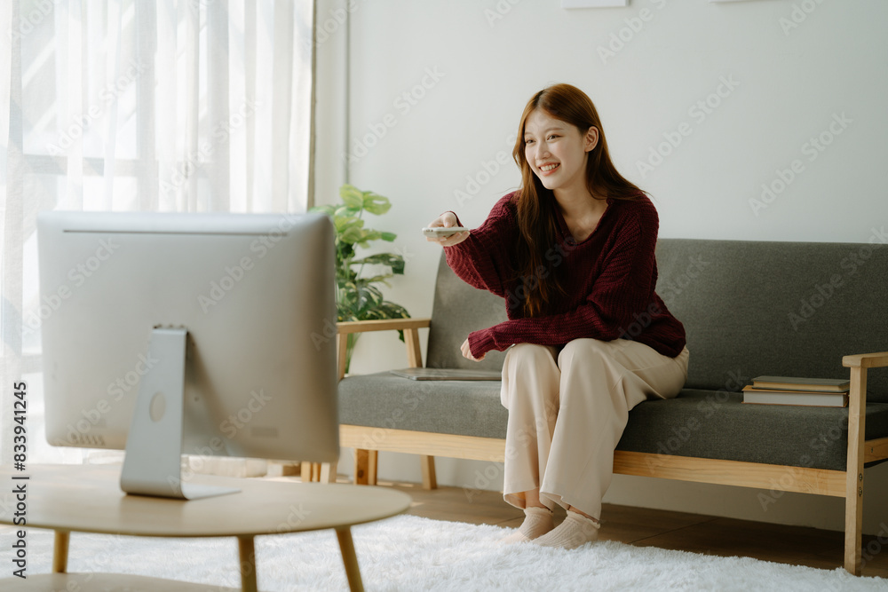 Portrait of beautiful smiling Asian woman relaxing on sofa in living room, watching TV Portrait of beautiful smiling Asian woman relaxing on sofa in living room, watching TV