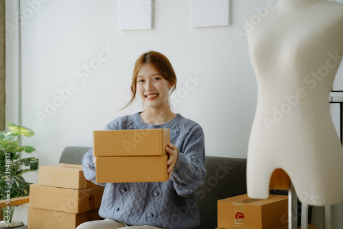 Startup small business entrepreneur or freelance Asian woman using a laptop with box, Young success Asian woman with her hand lift up, online marketing