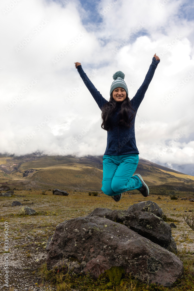 Young woman jumping with her arms raised after a mountain hike, concept of freedom, lifestyle, and travel Young woman jumping with her arms raised after a mountain hike, concept of freedom, lifestyle, and travel