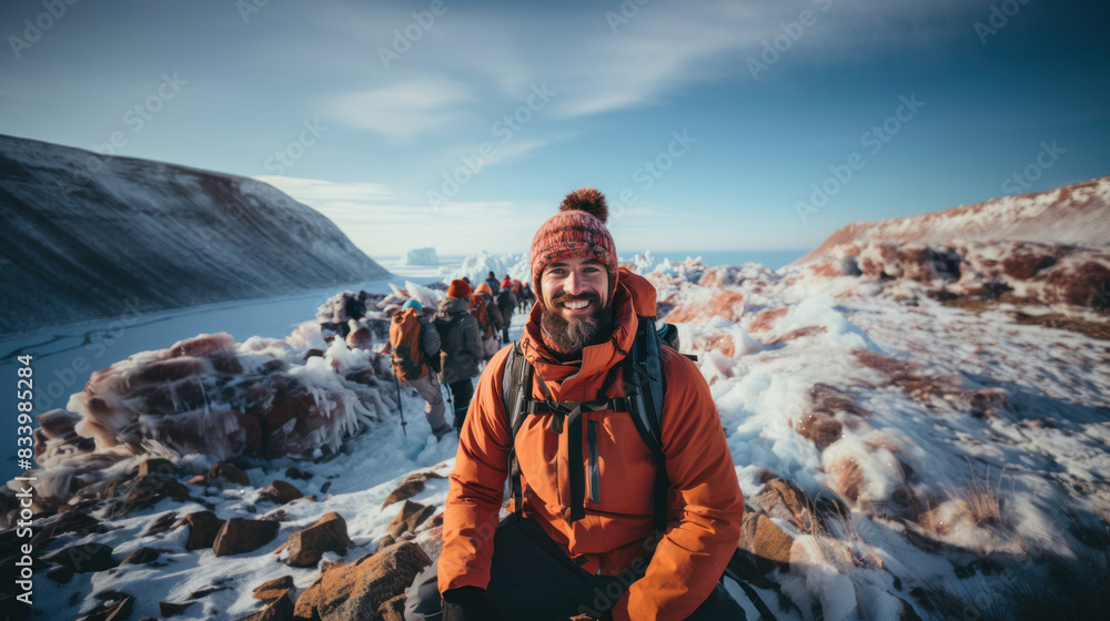 A person in a bright orange jacket is resting during an Arctic expedition with a group A person in a bright orange jacket is resting during an Arctic expedition with a group