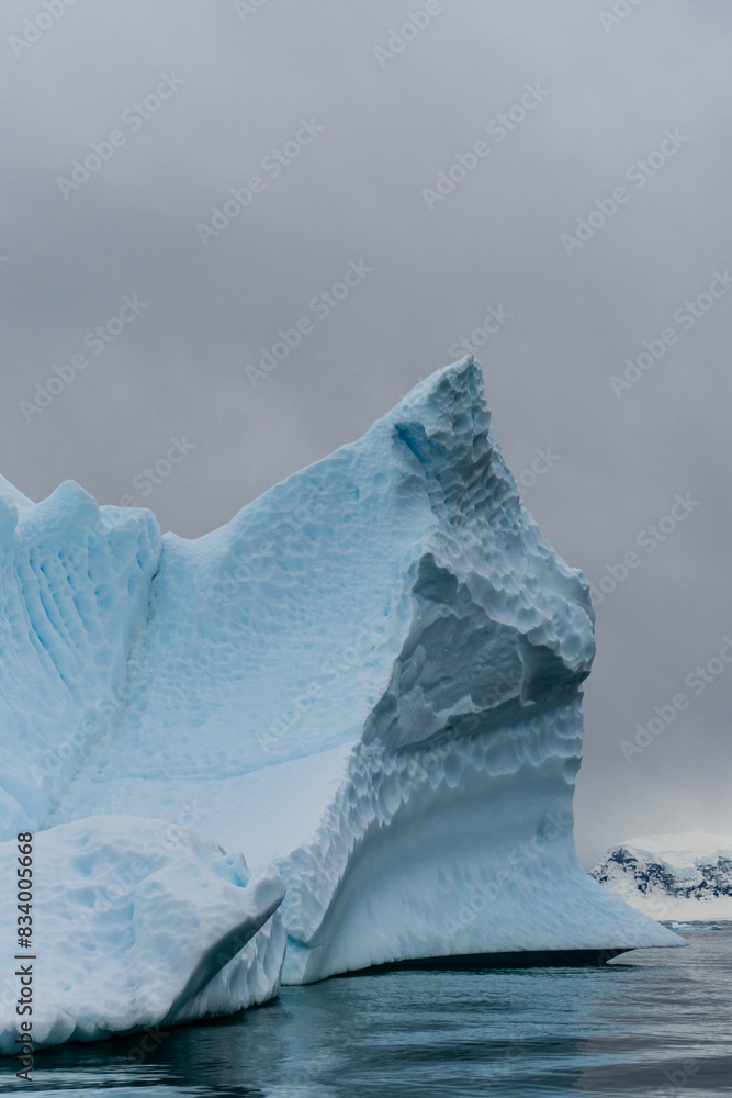 An Antarctic landscape shot near Cuverville island, highlighting mountains and icebergs.